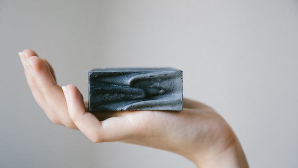 Man holding a dark charcoal soap bar